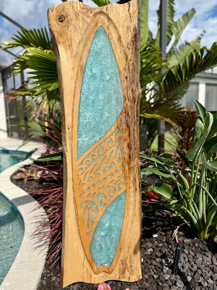 Tranquil Waters live-edge wood surfboard wall art with shimmering teal resin and carved tribal pattern